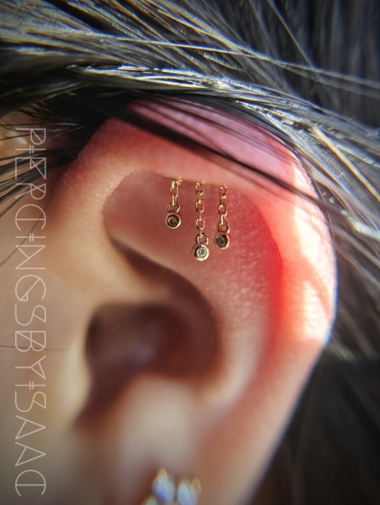 Helix ear piercings with gold cluster jewelry at Sideshow Tattoo and Piercing San Diego