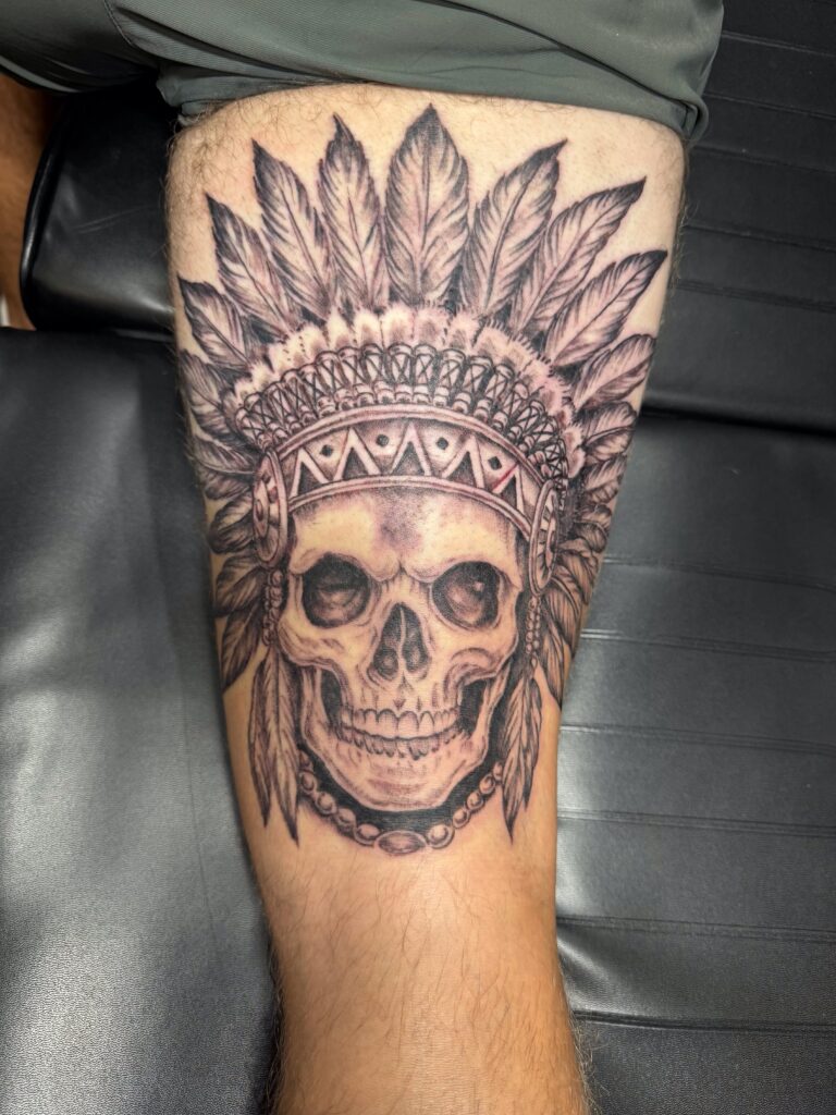 Skull with feather headdress forearm tattoo by Sideshow Tattoo and Piercing San Diego