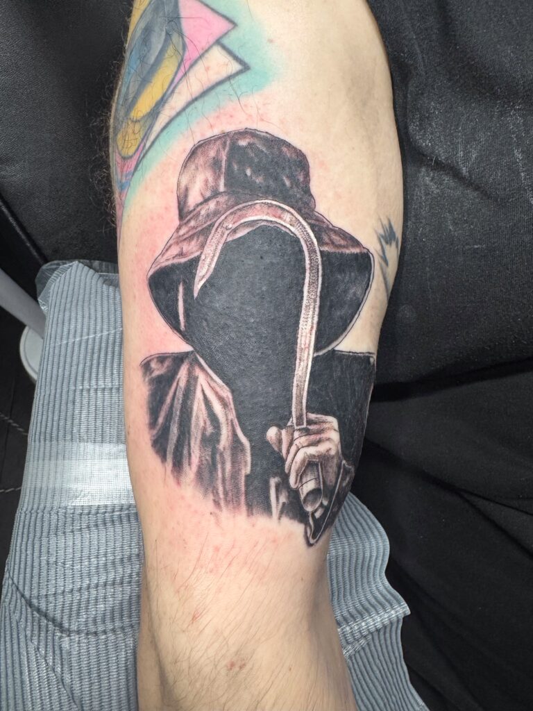 Black and grey reaper tattoo on upper arm by Sideshow Tattoo and Piercing San Diego