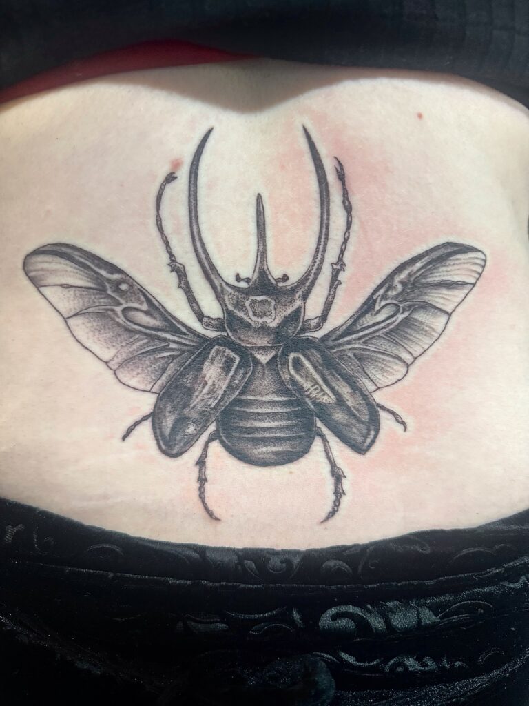 Black and grey beetle tattoo on lower back by Sideshow Tattoo and Piercing San Diego